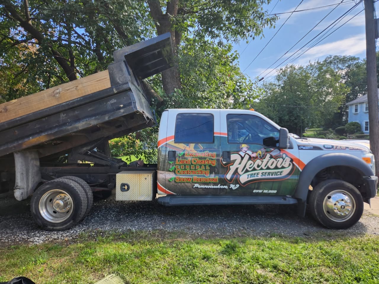 Hector’s branded tree-service truck with its dump bed raised
